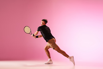 Image showing Young caucasian man playing tennis isolated on pink studio background, action and motion concept