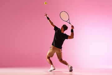 Image showing Young caucasian man playing tennis isolated on pink studio background, action and motion concept