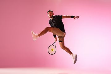 Image showing Young caucasian man playing tennis isolated on pink studio background, action and motion concept