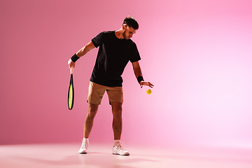 Image showing Young caucasian man playing tennis isolated on pink studio background, action and motion concept