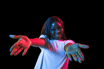 Image showing African young woman\'s portrait on dark studio background in neon. Concept of human emotions, facial expression, youth, sales, ad.