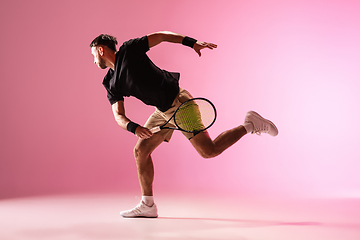 Image showing Young caucasian man playing tennis isolated on pink studio background, action and motion concept