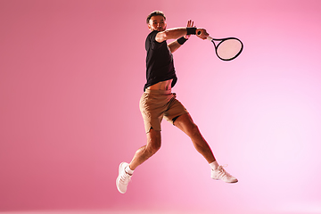 Image showing Young caucasian man playing tennis isolated on pink studio background, action and motion concept