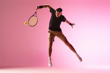 Image showing Young caucasian man playing tennis isolated on pink studio background, action and motion concept