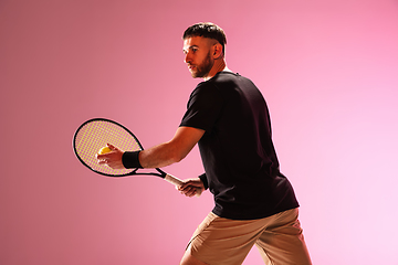 Image showing Young caucasian man playing tennis isolated on pink studio background, action and motion concept