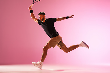 Image showing Young caucasian man playing tennis isolated on pink studio background, action and motion concept