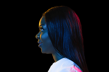 Image showing African young woman\'s portrait on dark studio background in neon. Concept of human emotions, facial expression, youth, sales, ad.