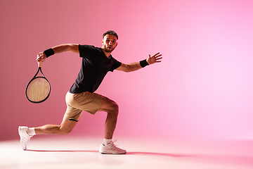 Image showing Young caucasian man playing tennis isolated on pink studio background, action and motion concept