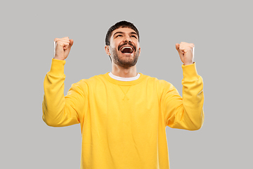 Image showing happy man in yellow sweatshirt celebrating victory