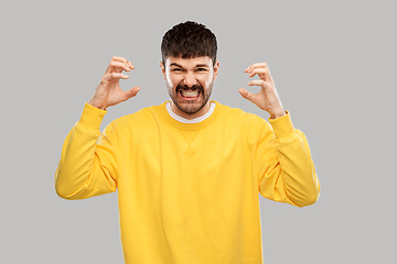 Image showing angry young man in yellow sweatshirt over grey