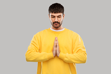 Image showing man in yellow sweatshirt meditating or praying