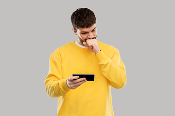 Image showing puzzled young man with smartphone