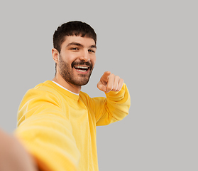 Image showing happy young man in yellow sweatshirt making selfie