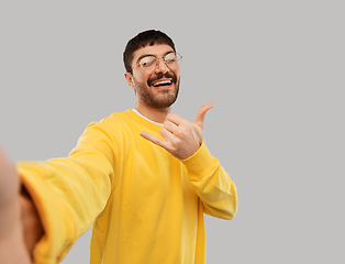 Image showing happy young man in yellow sweatshirt making selfie