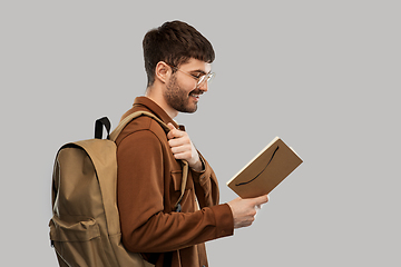 Image showing smiling young man with backpack reading diary