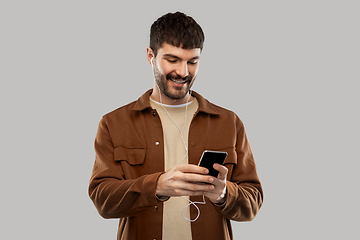 Image showing smiling young man with earphones and smartphone