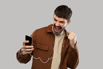 Image showing smiling young man with earphones and smartphone