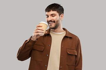 Image showing happy young man drinking coffee from takeaway cup