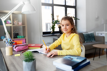 Image showing student girl with book writing to notebook at home