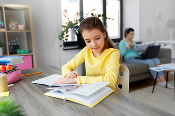 Image showing student girl with book writing to notebook at home