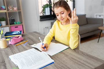 Image showing student girl with book writing to notebook at home