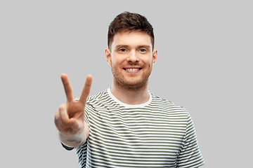 Image showing young man showing peace over grey background