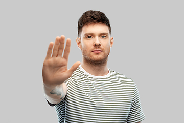 Image showing serious young man showing stop gesture