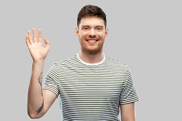 Image showing smiling young man in striped t-shirt waving hand