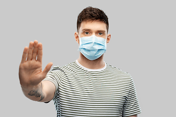 Image showing man in protective medical mask making stop gesture