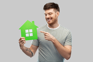 Image showing smiling young man holding green house icon