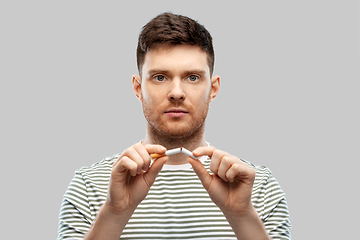 Image showing young man in striped t-shirt braking cigarette