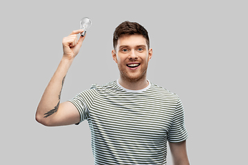 Image showing smiling young man holding lighting bulb