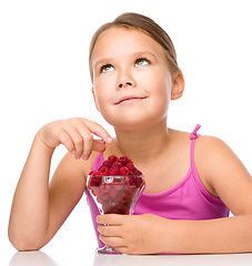 Image showing Happy little girl is eating raspberries