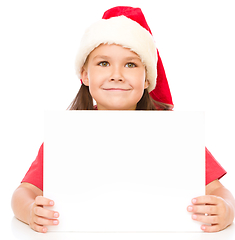 Image showing Little girl in santa hat is holding blank board