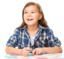 Image showing Girl is writing on color stickers using pen