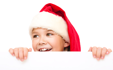 Image showing Little girl in santa hat is holding blank board