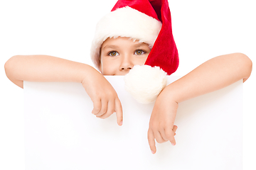Image showing Little girl in santa hat is holding blank board