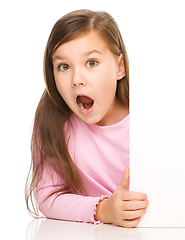 Image showing Little girl is looking out from the blank banner