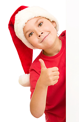 Image showing Little girl in santa hat is holding blank board