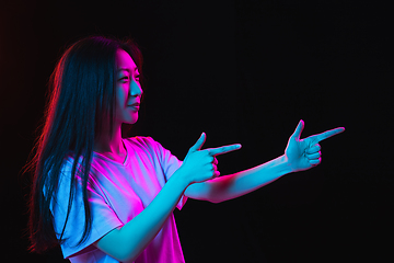 Image showing Asian young woman\'s portrait on dark studio background in neon. Concept of human emotions, facial expression, youth, sales, ad.