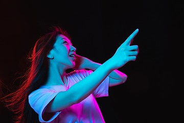 Image showing Asian young woman\'s portrait on dark studio background in neon. Concept of human emotions, facial expression, youth, sales, ad.