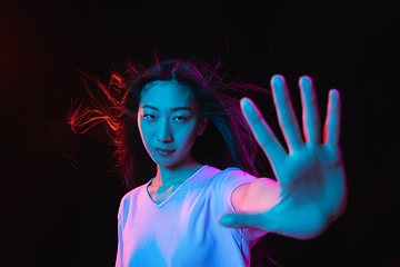 Image showing Asian young woman\'s portrait on dark studio background in neon. Concept of human emotions, facial expression, youth, sales, ad.