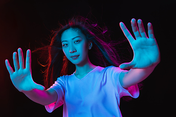 Image showing Asian young woman\'s portrait on dark studio background in neon. Concept of human emotions, facial expression, youth, sales, ad.