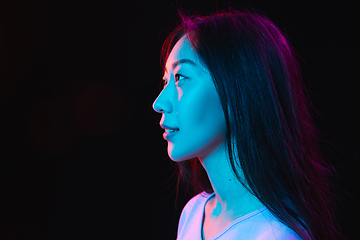 Image showing Asian young woman\'s portrait on dark studio background in neon. Concept of human emotions, facial expression, youth, sales, ad.