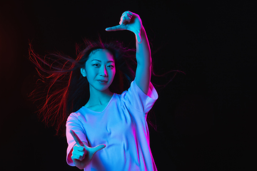 Image showing Asian young woman\'s portrait on dark studio background in neon. Concept of human emotions, facial expression, youth, sales, ad.