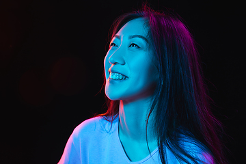 Image showing Asian young woman\'s portrait on dark studio background in neon. Concept of human emotions, facial expression, youth, sales, ad.