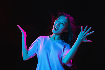 Image showing Asian young woman\'s portrait on dark studio background in neon. Concept of human emotions, facial expression, youth, sales, ad.