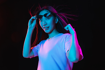 Image showing Asian young woman\'s portrait on dark studio background in neon. Concept of human emotions, facial expression, youth, sales, ad.