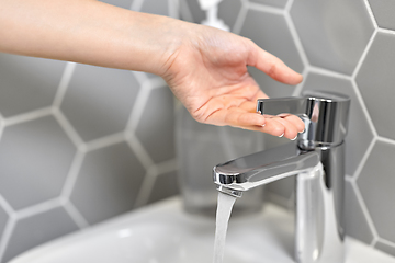 Image showing close up of woman's hand opening water tap