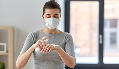 Image showing close up of woman in mask spraying hand sanitizer